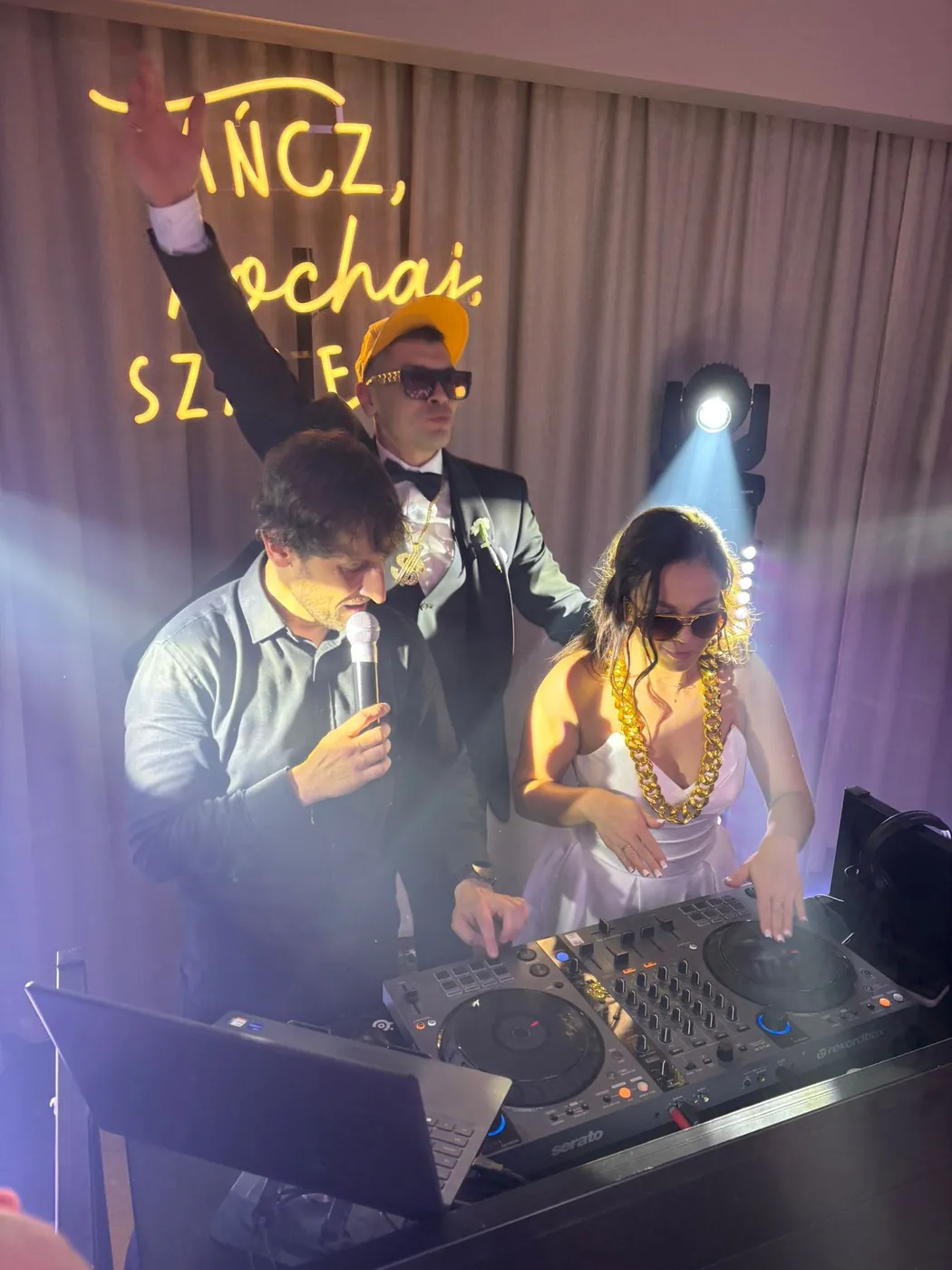 Para młoda w okularach przeciwsłonecznych bawi się przy konsoli DJ-a razem z wodzirejem