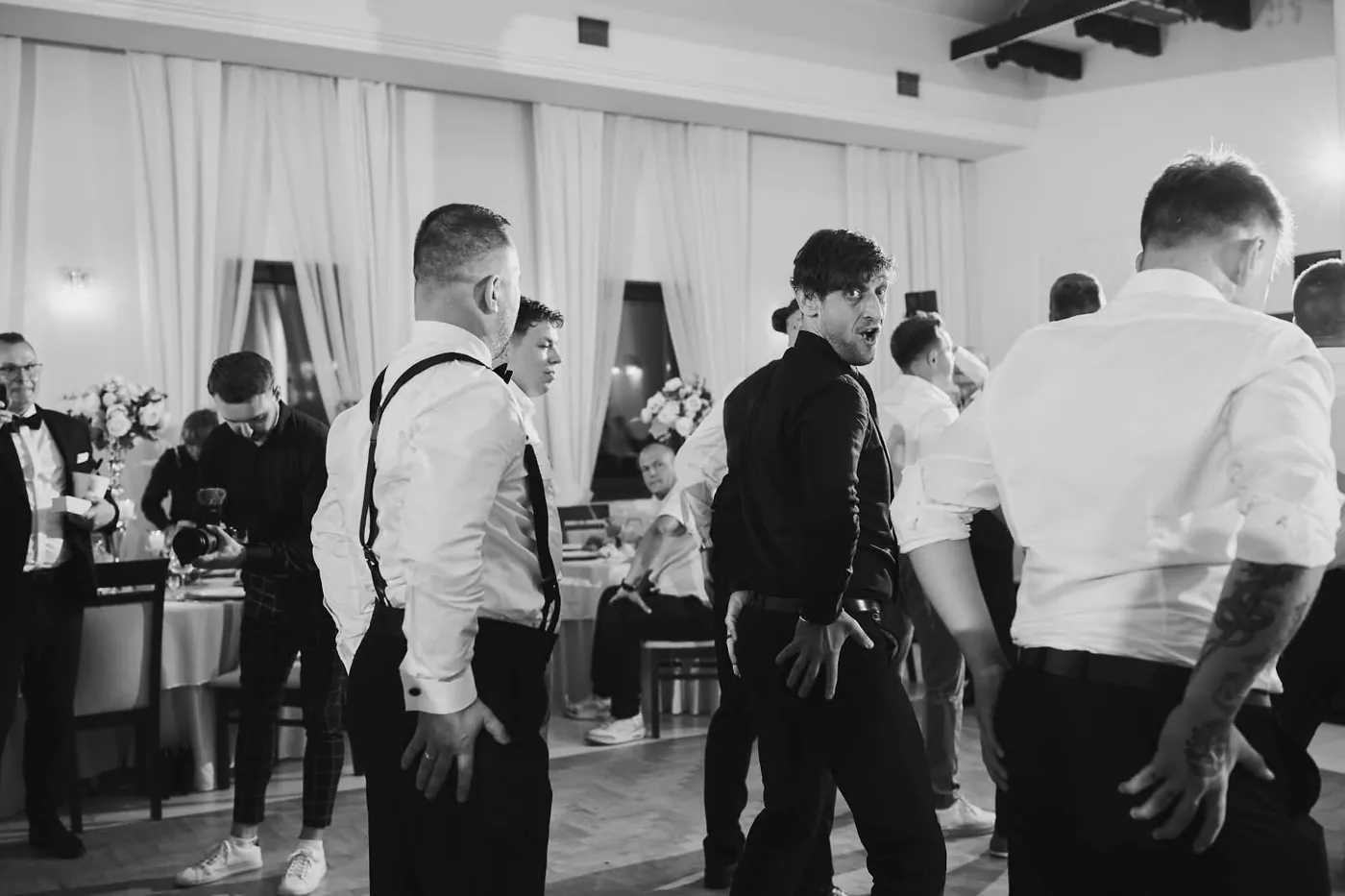 Wodzirej tańczy z gośćmi weselnymi, zdjęcie czarno-białe