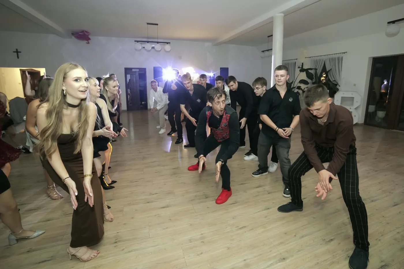 Goście powtarzają kroki za wodzirejem w czerwonych butach